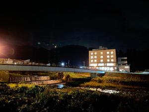 山之内町奥莫达卡酒店的一座河上的桥梁,晚上有一座建筑