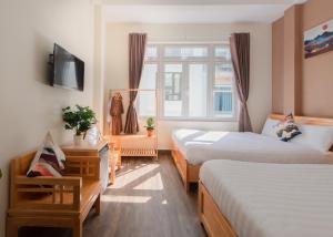 大叻Moc Thach Hostel Dalat的酒店客房设有两张床和电视。