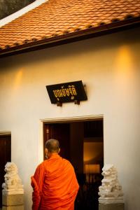 尖竹汶Punyashthiti villa的站在一座建筑前身的橙色长袍中的僧侣
