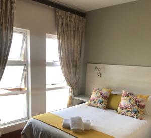 比勒陀利亚314克拉克旅馆的一间卧室配有带2个枕头的床和2个窗户。