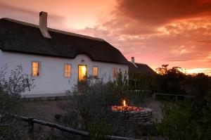 De Hoop Nature ReserveDe Hoop Collection - Vlei Cottages的日落时在屋前有火的白色房子