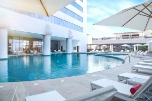 迪拜Al Jaddaf Rotana Suite Hotel的游泳池,带椅子和遮阳伞