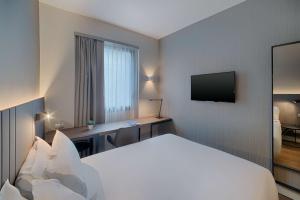 巴勒莫NH巴勒莫酒店的酒店客房配有一张床、一张书桌和一台电视。