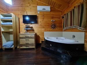 谢莫纳城בקתות היובל的带浴缸的浴室和木墙电视。