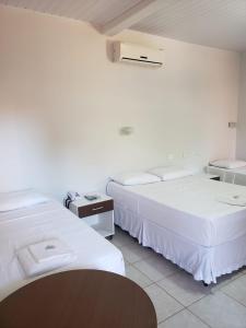 米兰达Pantanal Hotel的配有2张床的白色墙壁和桌子