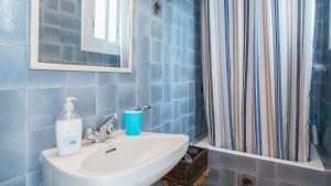 锡切斯桑尼公寓的蓝色瓷砖浴室设有水槽和淋浴