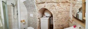 孔韦尔萨诺Fascino Antico的浴室设有石墙、卫生间和水槽。