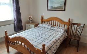 恩尼斯克朗Cosy 2-Bed Cottage in Sligo的一间卧室配有一张木床和一把椅子