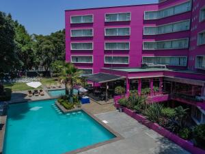 普埃布拉Hotel Real de Puebla的一座粉色建筑前的带游泳池的酒店