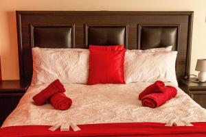 鲸湾港Stay Cleverly Self Catering Apartments的一张带红色枕头的床和红色毛巾