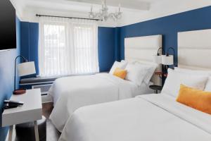 纽约voco The Franklin New York, an IHG Hotel的一间卧室设有两张床,拥有蓝色的墙壁。