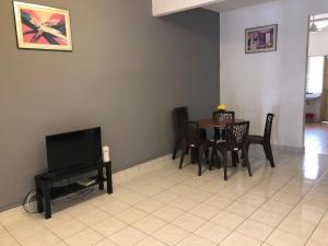彭亨Bentong Makmur Guesthouse的客厅配有桌椅和电视。