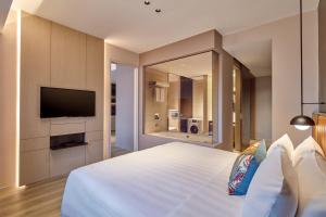 新加坡Pan Pacific Serviced Suites Orchard, Singapore的卧室配有一张白色大床和一台平面电视。
