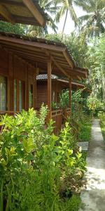 珀尼达岛Nusa Penida Pudak Nature Bungalow的一座带门廊和一些植物的木屋