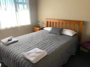 OwakaCatlins Inn的一间卧室配有一张床,上面有两条毛巾