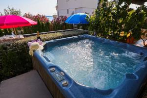 科济诺Luton Apartment Zadar Kozino Heating Pool & Jacuzzi的后院的按摩浴缸,配有遮阳伞