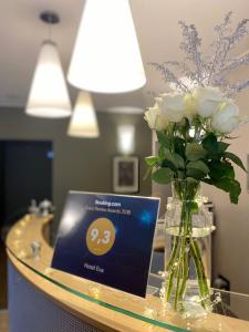 彼尔姆伊娃酒店的一张桌子,上面有白色玫瑰花瓶和一张卡片