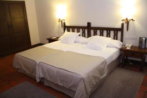 阿维拉帕拉多阿维拉酒店的卧室配有一张带白色床单和枕头的大床。