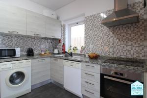 巴雷鲁Chez Nous - Guest House的厨房配有白色橱柜、洗衣机和烘干机