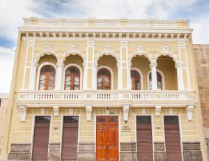 基多Hotel Casona 1914的黄色的建筑,设有红色的门和阳台