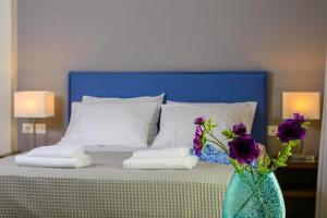 伊罗达Elounda Colour Apartments的花瓶里带蓝色床头板和紫色花的床铺