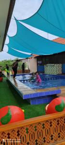 哥打巴鲁HOMESTAY Kb Wakaf Kayu的一群儿童在游泳池的伞下玩耍
