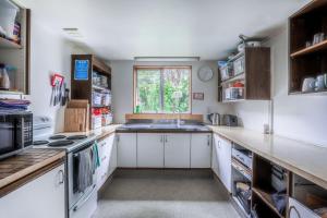 皇后镇Aspen Lodge Backpackers的厨房配有白色橱柜、水槽和窗户。