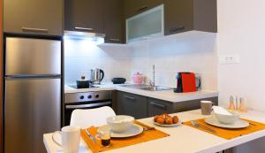 伊罗达Elounda Colour Apartments的厨房配有桌子和不锈钢冰箱。