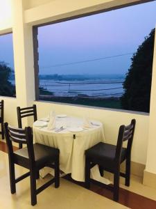 MelāgharLake Side Resort Neermahal的一张带两把椅子的白色桌子和大窗户