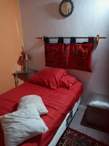 内乌肯La Casita的一间卧室配有一张带红色床单和枕头的床。