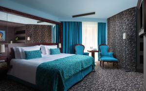 圣彼得堡多米纳圣彼得堡酒店的酒店客房,配有一张床和两张蓝色椅子