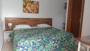 瓜鲁雅Pousada Villa Virgínia Guarujá的一间卧室配有一张带彩色毯子的床