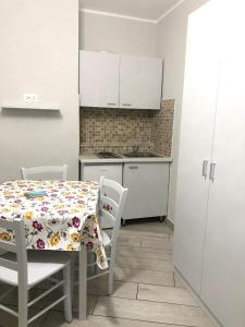 那不勒斯One bedroom apartement with wifi at Napoli的一间带桌椅的厨房和一间带白色橱柜的厨房