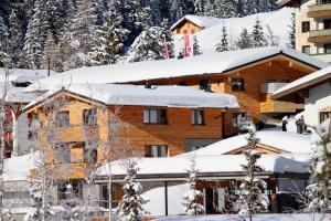 莱赫阿尔贝格阿尔卑斯山附近莱赫住宿加早餐旅馆的雪覆盖的建筑,有雪覆盖的屋顶
