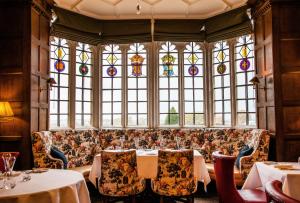 切尔滕纳姆艾伦博霍公园酒店的餐厅配有沙发、桌子和彩色玻璃窗
