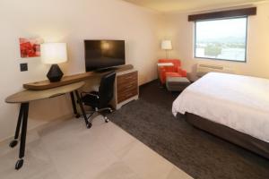 蒙特雷Holiday Inn & Suites - Monterrey Apodaca Zona Airport, an IHG Hotel的酒店客房配有一张床和一张书桌及一台电视