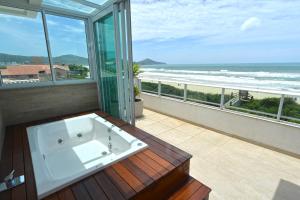 邦比尼亚斯Hospedaria Home Suites Mariscal的海景阳台上设有浴缸。
