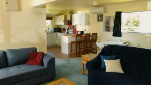 WhakatahuriCountry Cottage Rotorua的一间带两张沙发的客厅和一间厨房