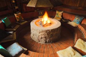 法尔瓦特Valamanzi Lodge in Nyati Wilderness的一个带椅子的房间的大火坑