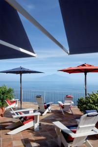 索伦托梅森米纳维塔酒店的庭院里摆放着一组椅子和遮阳伞
