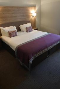波克灵顿The Feathers的一张大床,位于酒店客房内,配有两个枕头