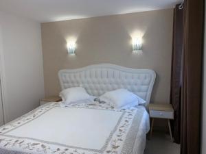 万泽内姆Coeur d'Alsace Colmar Vignobles Ouest avec terrasses的一张白色的床,配有两个枕头和墙上的两盏灯