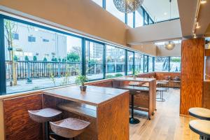 东京Wise Owl Hostels River Tokyo的餐厅设有大窗户、桌子和凳子