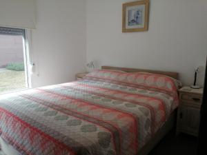 皮里亚波利斯Descanso en Piriápolis的一间卧室配有带条纹棉被的床和窗户