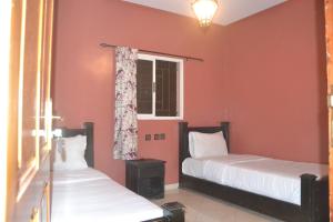 达赫拉Inyan Dakhla Hotel的宿舍间的两张床,设有红色的墙壁和窗户。