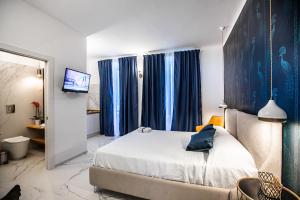 锡拉库扎Domus Vittoria Siracusa的一间卧室配有一张带蓝色窗帘的床和电视。