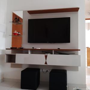 乌巴图巴APTO PERTINHO DA PRAIA - Lindo e Equipado! Internet 400mb e 3 Tvs - Completo! TV a Cabo的客厅的墙上配有电视