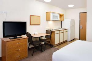 韦恩堡WoodSpring Suites Fort Wayne的酒店客房设有一张书桌、一台电视和一间厨房