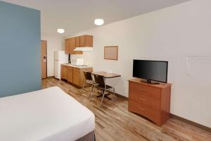 Pleasant HillWoodSpring Suites Des Moines Pleasant Hill的配有一张床和一台平面电视的酒店客房