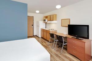 Pleasant HillWoodSpring Suites Des Moines Pleasant Hill的酒店客房配有一张床和一张书桌及一台电视